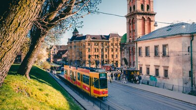Трамвай іде вулицею в центральній частині міста. На задньому плані старовинна вежа і будинки.