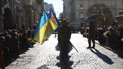 На площі біля Гарнізонного храму люди прощаються з воїном, перед труною військові несуть прапори