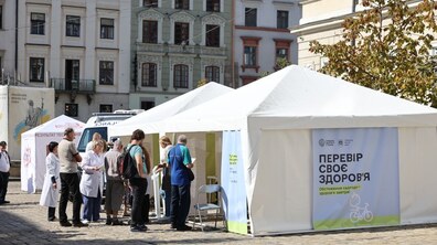 Люди стоять біля наметів з написом 