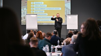 На сцені виступає мер Львова Андрій Садовий. Позаду нього демонстрація презентації із пріоритетними напрямками міста. Учасники в залі уважно слухають