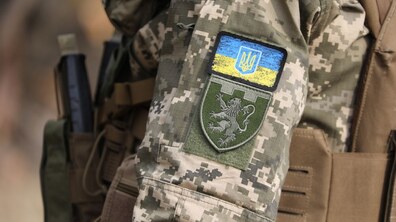 Рука військовослужбовця з нарукавним знаком Державний Прапор України та нарукавним знаком військової частини