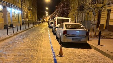 Автівки на одному з платних паркувальних майданчиків міста. Нічна вулиця освітлена теплим світлом ліхтарів