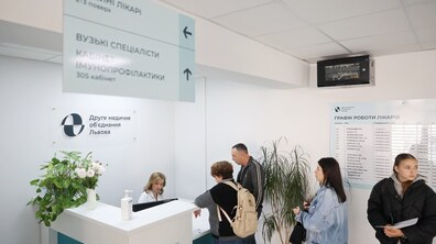 Двоє пацієнтів розмовляють з працівницею на рецепції у Другому медичному об’єднанні Львова, ще двоє – стоять у черзі