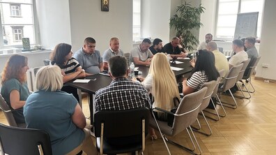 У великому залі за довгим столом люди спілкуються на тему функціонування закладу. Присутні майже два десятки мешканців та представників міста.