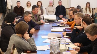 за великим столом у міській раді сидить багато людей, серед яких - мешканці та посадовці Львівської міської ради, по центру мер Львова активно спілкується з мешканцем