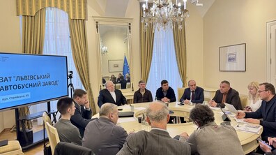 Більше десятка учасників зустрічі, членів робочої групи щодо розвитку території Львівського автобусного заводу, за круглим столом у Білій залі Львівської міської ради. На екрані збоку презентація, напис “Львівський автобусний завод”
