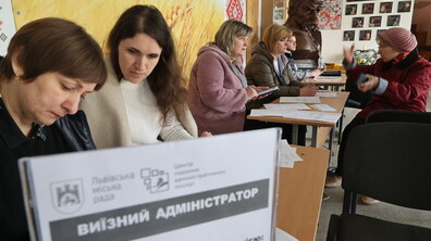 Виїзний ЦНАП на вул. Трильовського: за столами сидять адміністраторки та спілкуються з мешканцями, на столі лежать різні документи. На передньому плані видно табличку з написом «Виїзний адміністратор»