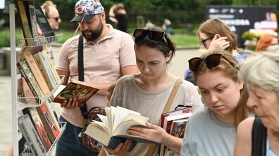 Люди розглядають та обирають книжки під час книгообміну. Відвідувачі гортають видання, тримають придбані книги, а поруч розміщені стелажі з різноманітною літературою.