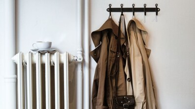 ілюстративне фото про початок опалювального сезону: батареї у квартирі біля вішалки, на якій висять пальто