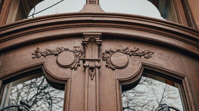 Фрагмент відреставрованої 100-літньої дерев'яної брами на вул. Вороного у Львові. На зображенні видно верхню частину брами з різьбленим декором та секціями зі скла