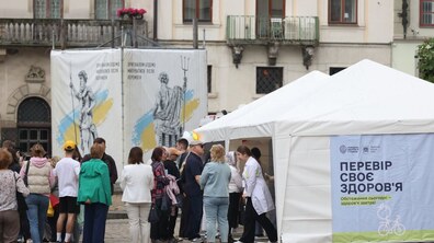 Люди стоять біля наметів з написом 