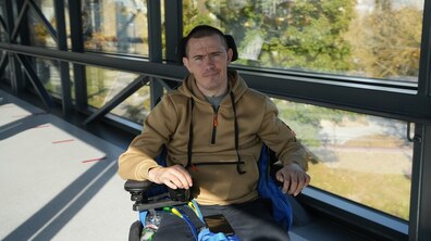 Захисник Дмитро Пироженко сидить на кріслі колісному в центрі UNBROKEN та усміхається