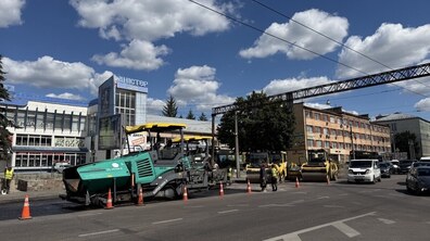 Ремонтні роботи на вул. Городоцькій. На одній зі смуг руху працює асфальтоукладальник, позаду нього стоять дорожні катки та інша спецтехніка. Робочу зону відокремлено помаранчевими конусами, поруч працюють дорожники у світловідбивних жилетах. Іншими смугами продовжує рухатися транспорт.