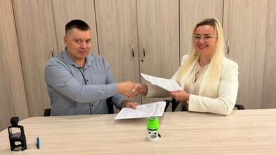 Директорка ЛКП «Львівелектротранс» Ірина Іванишин та директор Львівського міжрегіонального вищого професійного училища залізничного транспорту Петро Росіцький сидять за столом у сучасному офісі. Вони тримають підписані примірники Меморандуму та тиснуть одне одному руки.