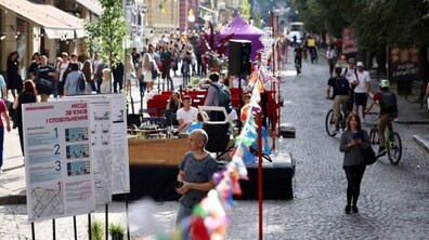 Фотокадр із попереднього «Дня вулиці Січових Стрільців». Тут облаштовано пішохідну зону з інформаційними стендами, вуличними меблями та гірляндами з прапорців. Уздовж вулиці мешканці прогулюються, відпочивають на облаштованих локаціях та пересуваються на велосипедах.