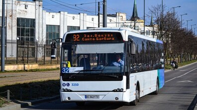 Білий низькопідлоговий автобус №20 їде вулицею, ліворуч видно будівлі