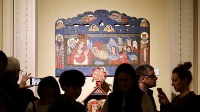 На стіні висить один з експонатів виставки, на якому забражена картира Різдва. Довкола екпонату багато людей