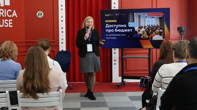 Вікторія Довжик, очільниця управління фінансової політики ЛМР, ділиться досвідом із учасниками резиденції. Позаду – демонстрація презентації. Навпроти – учасники зосереджено слухають лекцію