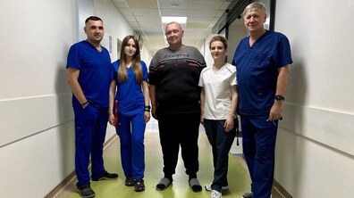 Пан Богдан (по центру) разом із медиками стоїть у коридорі лікарні