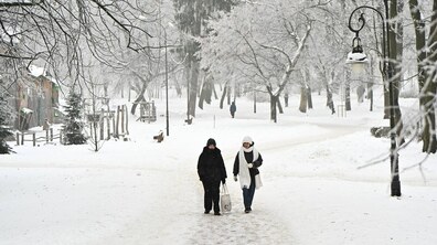 Двоє жінок йдуть засніженим парком Франка у Львові. Дерева та доріжки парку вкриті снігом. Зліва видно дитячий майданчик, а позаду - перехожі, які гуляють парком.