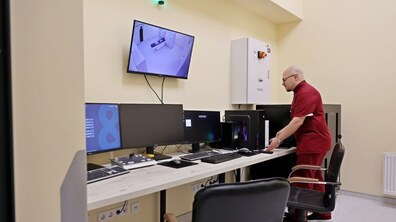 Медичний працівник стоїть біля великих моніторів, на яких спостерігає процес обстеження на спеціальному медичному обладнанні в Онкологічному центрі Першого медичного об’єднання Львова