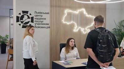 Двоє працівниць Львівського центру надання послуг учасникам бойових дій спілкуються з відвідувачем