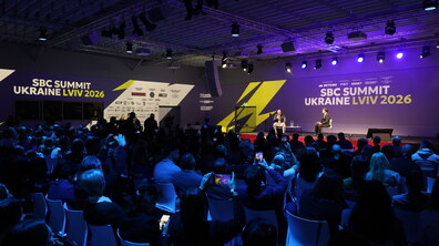 Учасники SBC Summit Ukraine сидять у залі та дивляться на сцену. На великих екранах по обидві сторони напис SBC Summit Ukraine 2026 Lviv.