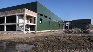 Будівля майбутнього сміттєпереробного заводу у Львові: видно залізобетонний каркас, цегляну кладку та сходи. Біля території ґрунтові проїзди, будівельні матеріали та техніка