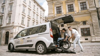 Біля історичної будівлі у Львові чоловік допомагає пасажиру на кріслі колісному заїхати по пандусу в спеціалізоване авто Uklon Inclusive. Фото ілюстративне.