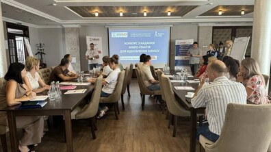 Учасники проєкту проходять навчання. Вони уважно слухають спікера, який демонтрує презентацію за допомогою проектора