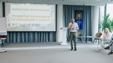 Перший заступник міського голови Львова Андрій Москаленко виступає на події. Перед ним сидять люди. Позаду екран з презентацією