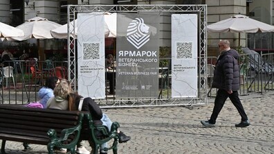 На площі Ринок стоїть стенд із написом «Ярмарок ветеранського бізнесу». Перед ним на лавці сидять люди. Поруч проходить чоловік