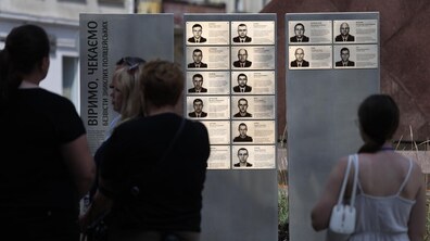 Люди розглядають стелу «Алея надії» з портретами та інформаційними табличками про зниклих безвісти поліцейських. На одному зі стендів великими літерами написано: «Віримо, чекаємо безвісти зниклих поліцейських».