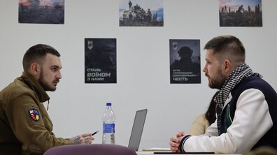 рекрутер спілкується з чоловіком, на фоні плакати із закликом долучатися до війська