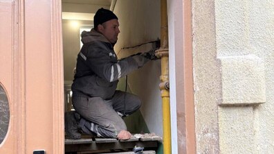 працівник підрядної організації проводить підготовчі роботи для укріплення стін у будинку на вул. Олени Степанівни, 24Б
