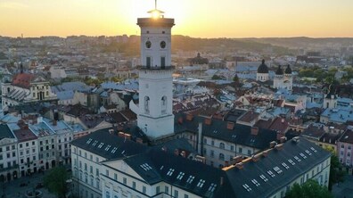 Панорама міста, на передньому плані будівля львівської ратуші над якою сходить сонце