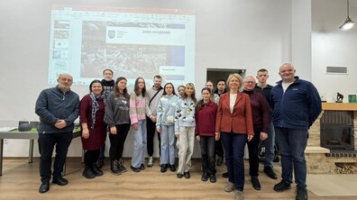 Спільне фото працівників Львівводоканалу, студентів та їх викладачів. За спинами групи — екран із проєкцією презентації. На слайді видно логотип і напис «Львівська міська рада» та заголовок «АКВА АКАДЕМІЯ», а також дата — 12 лютого 2026 року.