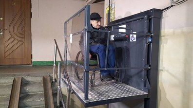 Чоловік на кріслі колісному випробовує підйомник.