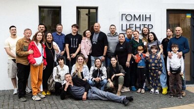 Спільне фото команди «Гомін Центру» перед будівлею установи. Дорослі й діти дивляться в камеру й усміхаються. На будівлі є табличка з написом «ГОМІН ЦЕНТР».