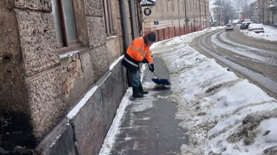 Працівник комунальної служби розчищає від снігу тротуар на одній із вулиць Львова