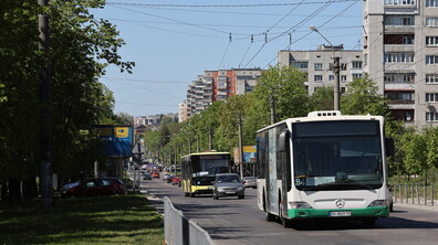 Вулиця Мазепи. З правого боку великий білий автобус №84 та сріблясте авто. Позаду них їде жовтий автобус №46. Над дорогою розміщені дроти для тролейбусів. Праворуч та вдалині - багатоповерхові житлові будинки.