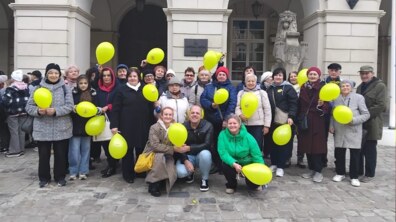 Спільне фото учасників заходу на площі Ринок, усі тримають в руках кульки жовтого кольору
