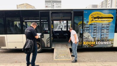 Інспектор управління транспорту ЛМР перевіряє міський автобус на зупинці, поки водій відкидає пандус для маломобільних пасажирів.