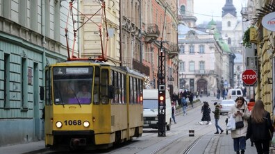 Вулиця Панви Беринди у Львові. По трамвайних коліях їде жовтий трамвай. Обабіч стоять багатоповерхові будинки пастельних кольорів, а на тротуарах видно перехожих і кілька автомобілів. На задньому плані височіють церковні вежі.