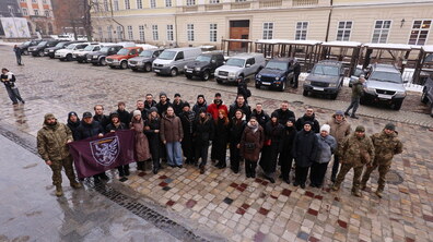 Організатори, хор “Гомін” та військові роблять фото. Позаду - автівки.
