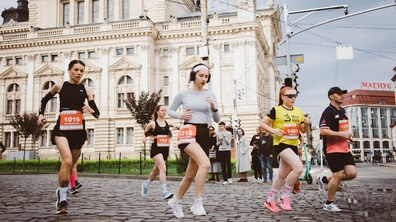 Учасники благодійного забігу біжать вулицею у центрі Львова. На передньому плані — кілька бігунів зі стартовими номерами, позаду видно історичну забудову міста