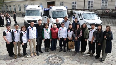 На площі Ринок стоїть група тайванських лікарів, представники тайванського фонду, Християнської медичної асоціації та міської влади Львова. Позаду припарковані три медичні автомобілі – мобільний стоматологічний комплекс, автомобіль швидкої допомоги і транспортний бус для медиків, які привезли тайванські лікарі для українських військових.