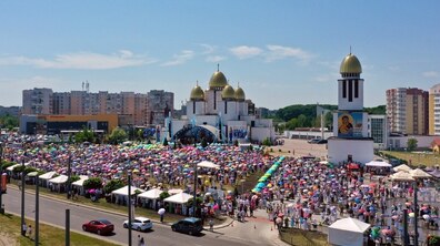 На площі перед храмом Різдва Пресвятої Богородиці зібралися тисячі вірян, які беруть участь в урочистій Архиєрейській Божественній Літургії з нагоди 25-річчя історичного візиту святого Івана Павла ІІ до України. На тлі храму із золотими банями та сцени видно велелюдне богослужіння просто неба