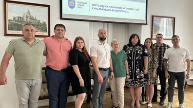 Представники Світловодської громади і представники львівської мерії позують для загального фото у приміщенні Львівської міської ради. Учасники стоять в один ряд. Позаду них на екрані демонструється презентація про безбар’єрність із написом: «Місто гідності та рівних можливостей: курс Львова на безбар’єрність».