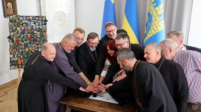 У Львівській ратуші, на фоні синьо-жовтих прапорів, учасники урочистої церемонії спільно здійснюють погашення ювілейної марки